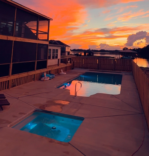 backyard pool and hot tub at sunset with waterfront views