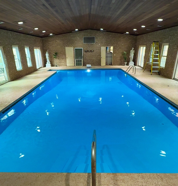 indoor pool in a brick-walled room with wood-paneled ceiling