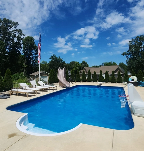 freeform pool with slide and lounge chairs in a residential backyard